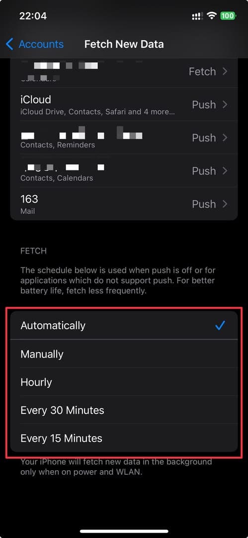 The image shows the 'Fetch New Data' settings on an iPhone, allowing users to control how often their device retrieves new information. The options include 'Automatically,' 'Manually,' 'Hourly,' 'Every 30 Minutes,' and 'Every 15 Minutes,' with 'Automatically' currently selected. The dark mode interface creates a sleek and modern aesthetic, emphasizing the phone's functionality.